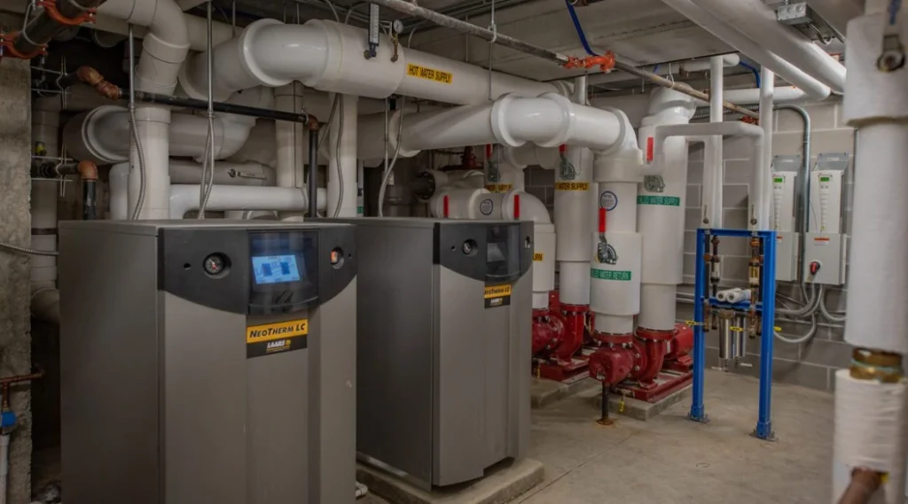 Skilled pipefitters installing hydronic piping in commercial mechanical room
